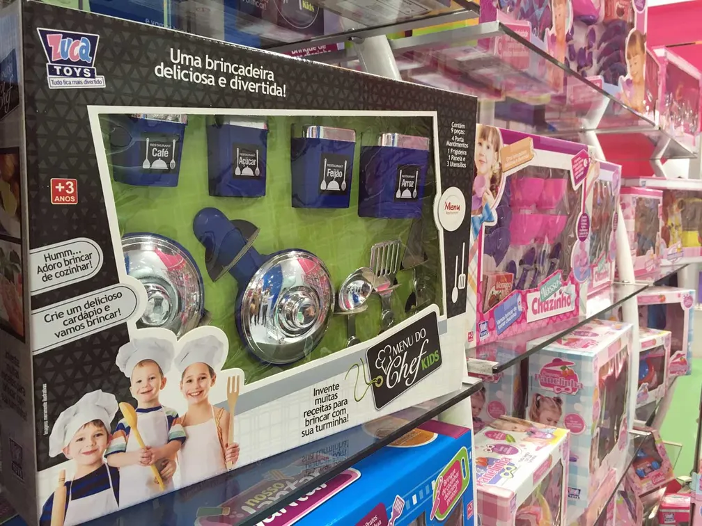 Prateleiras de uma loga de brinquedos, com brinquedos de cozinha nas cores azul e rosa.